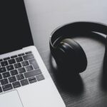 black wireless headphones beside MacBook Pro