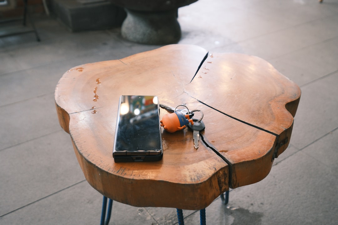 🕰️ Unearthing the Roots: A Brief History of Headphone Innovation by Headphone Brands Phone, keys, and an orange ball on a wooden table.